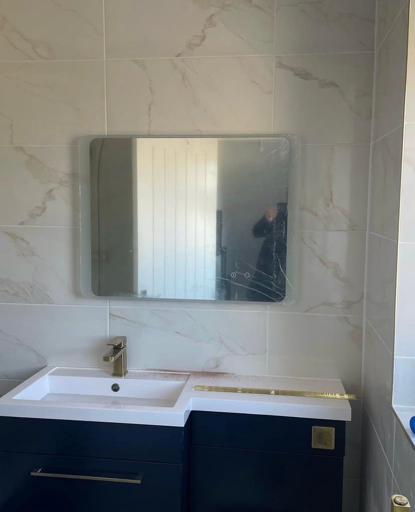 Navy vanity and basin with the mirror going up, protective film still on the glass