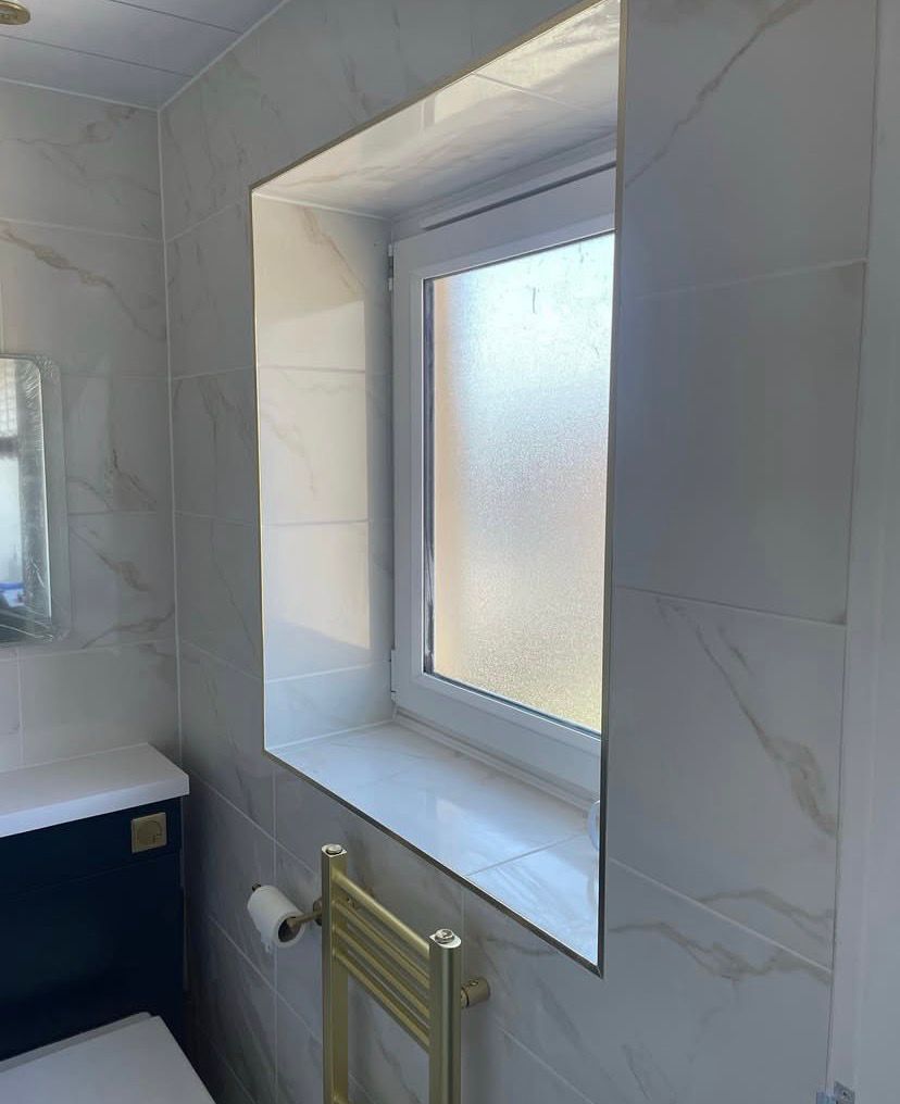 Fully tiled window reveal with brass trim and a brass heated towel rail below