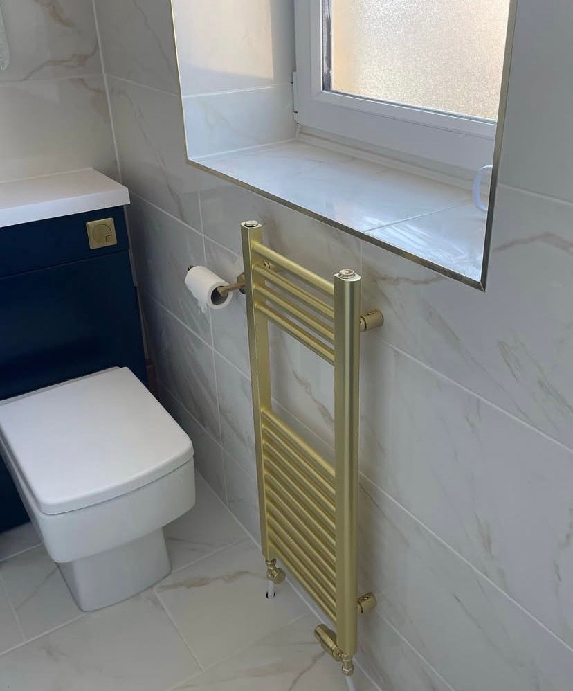 WC with a concealed cistern beside a brass heated towel rail and tiled window sill
