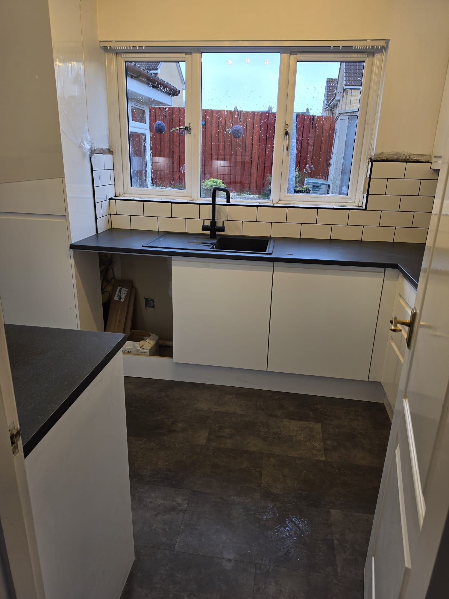 Metro splashback being tiled around the kitchen window with the black sink already fitted