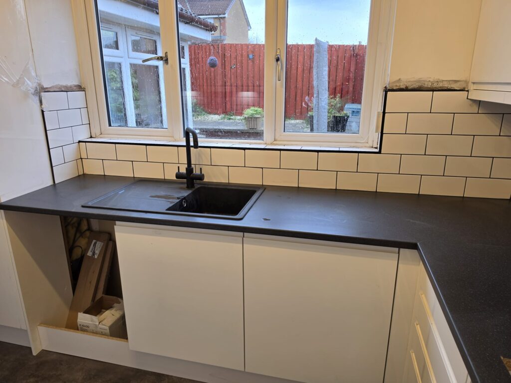 Metro splashback run and black composite sink under the kitchen window, units still being fitted